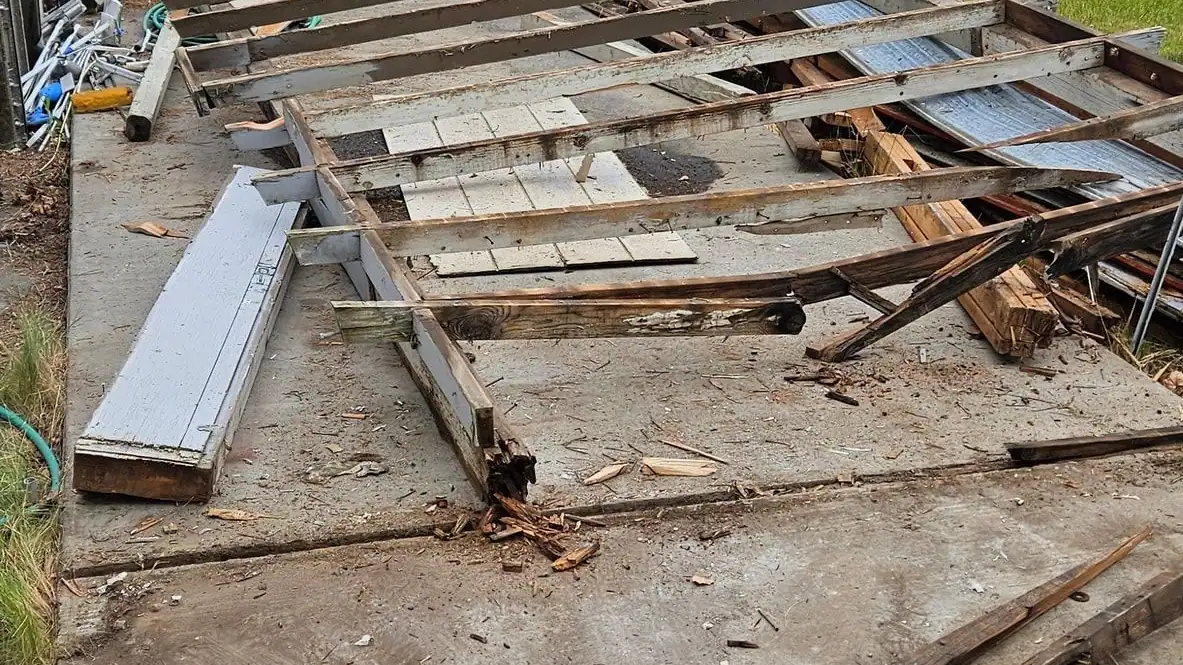 An old deck torn up, with broken boards and framing on the ground
