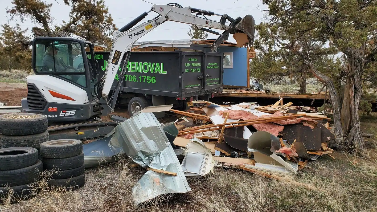 An excavator loading demolition debris into the Superior Junk Removal truck