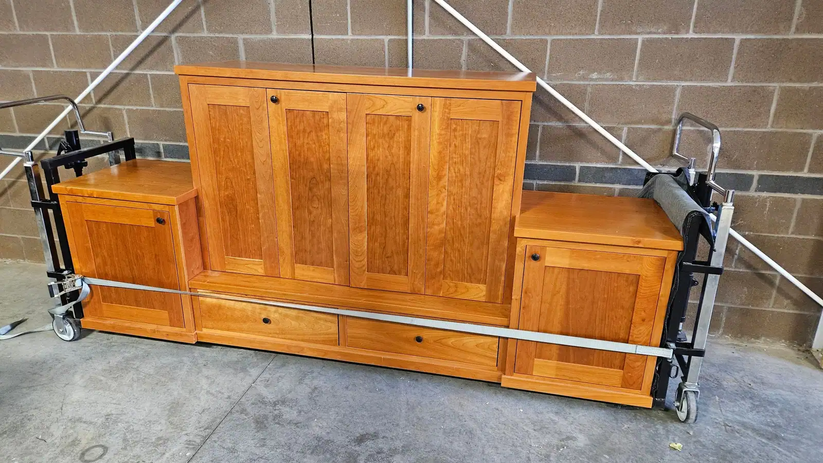A wood bed headboard and cabinets strapped to dollies