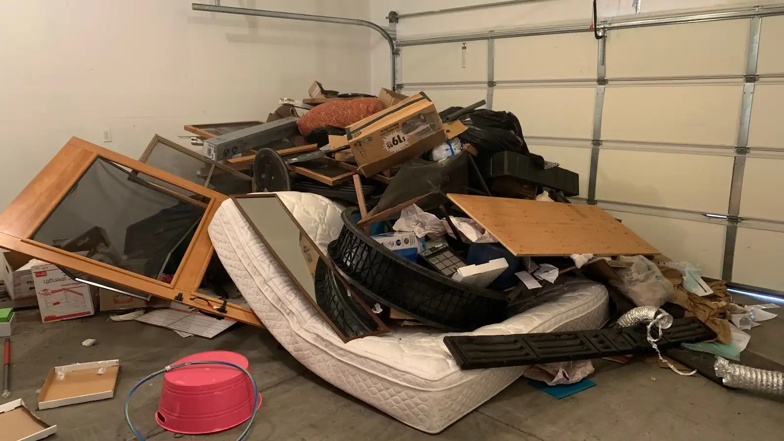 A garage piled with an old mattress, broken furniture and boxes