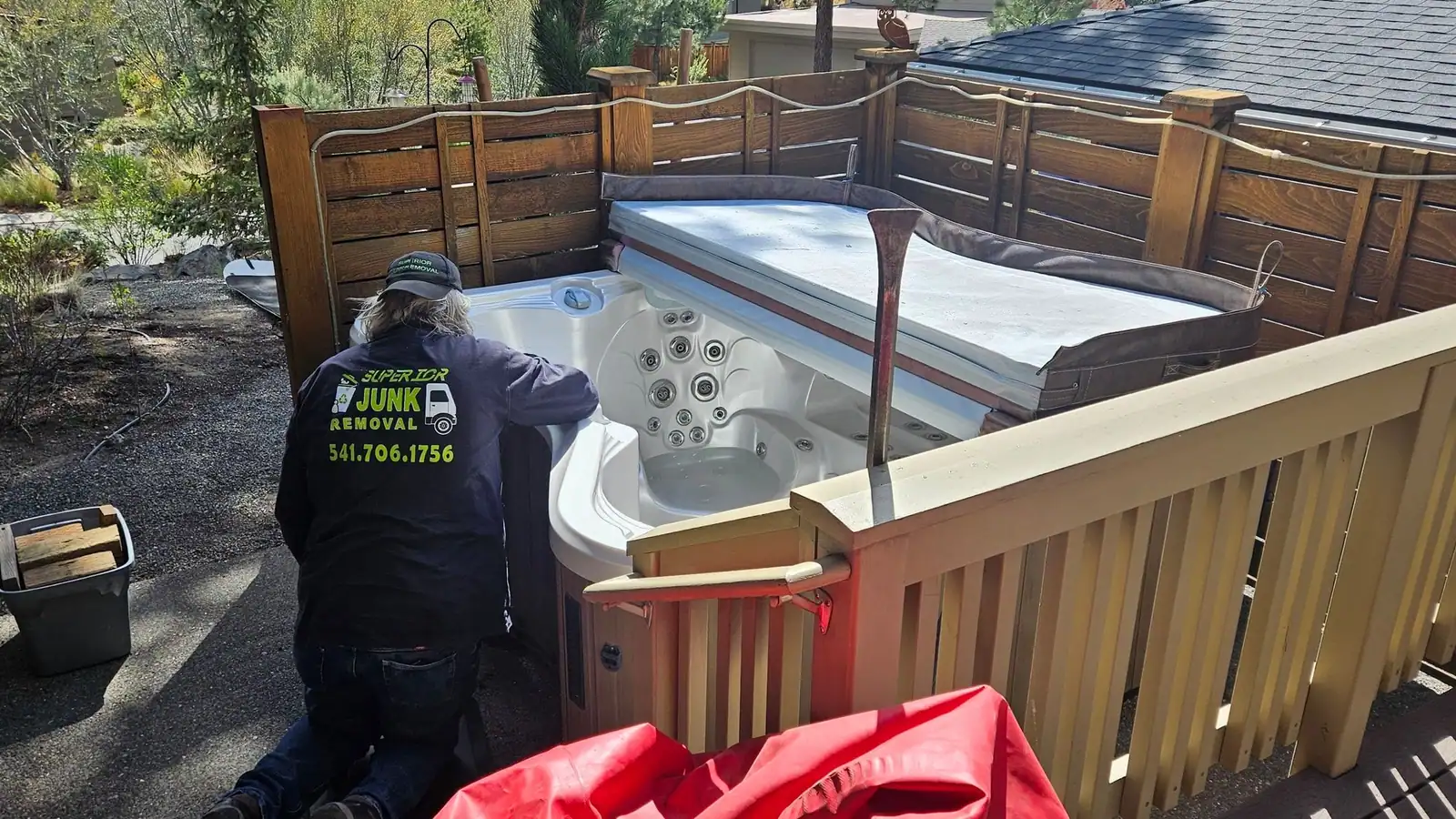 Calvin in a Superior Junk Removal hoodie taking apart an old hot tub on a deck