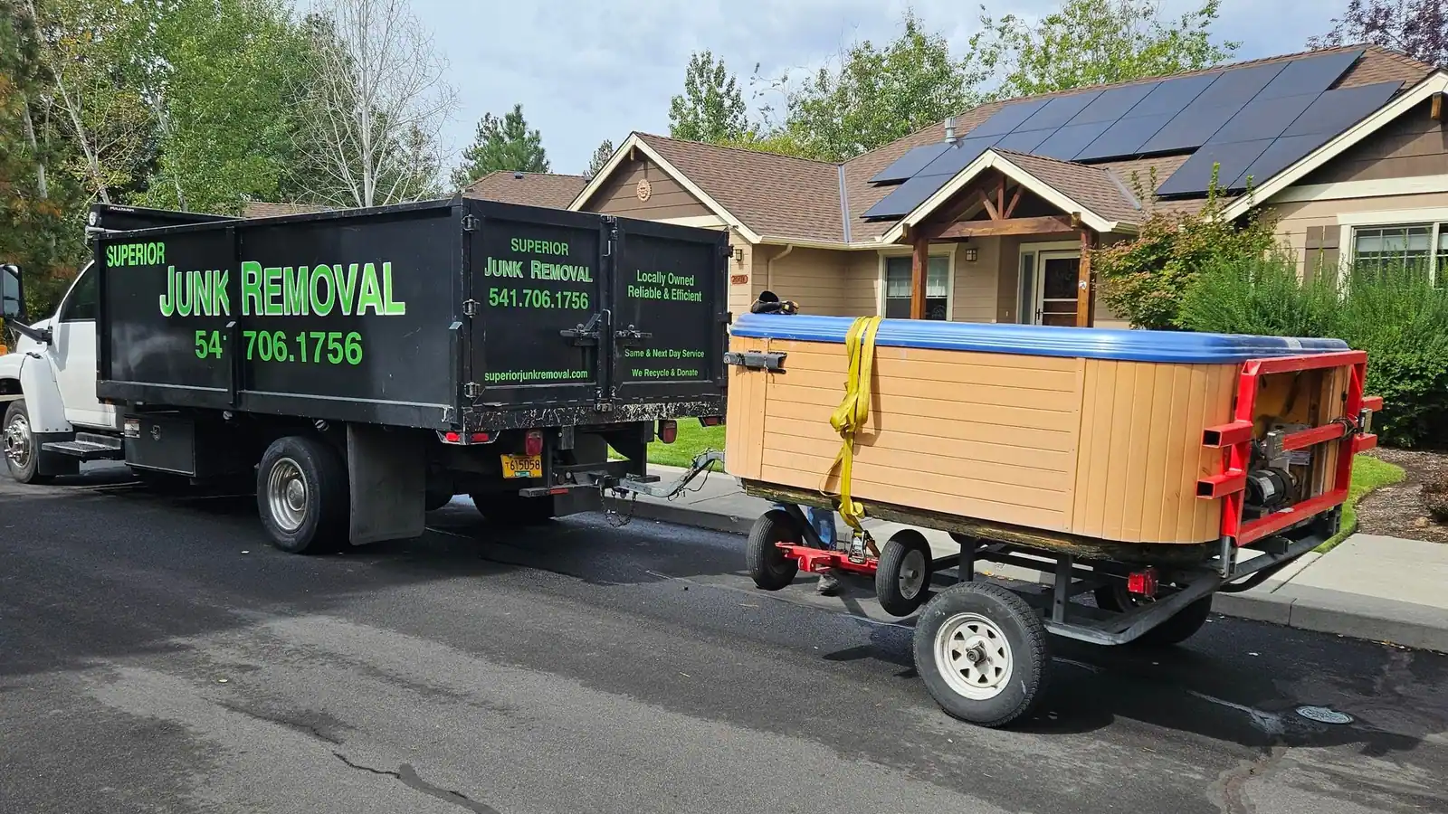 The Superior Junk Removal dump truck towing an old hot tub on a trailer