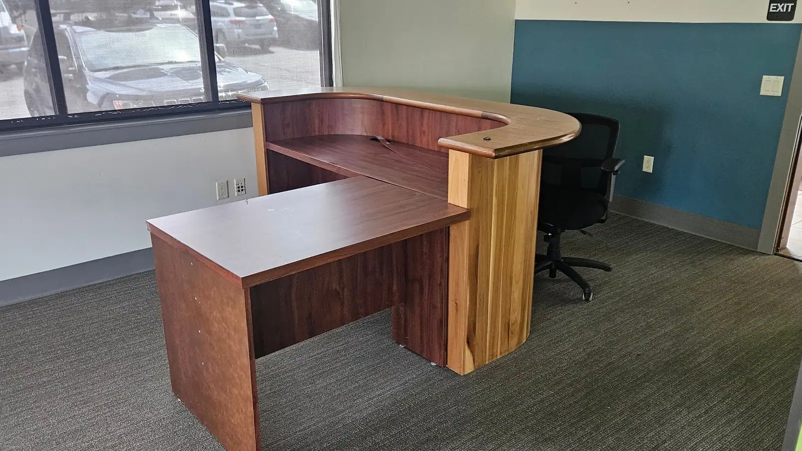 An L-shaped reception desk and chair in an office being cleared out