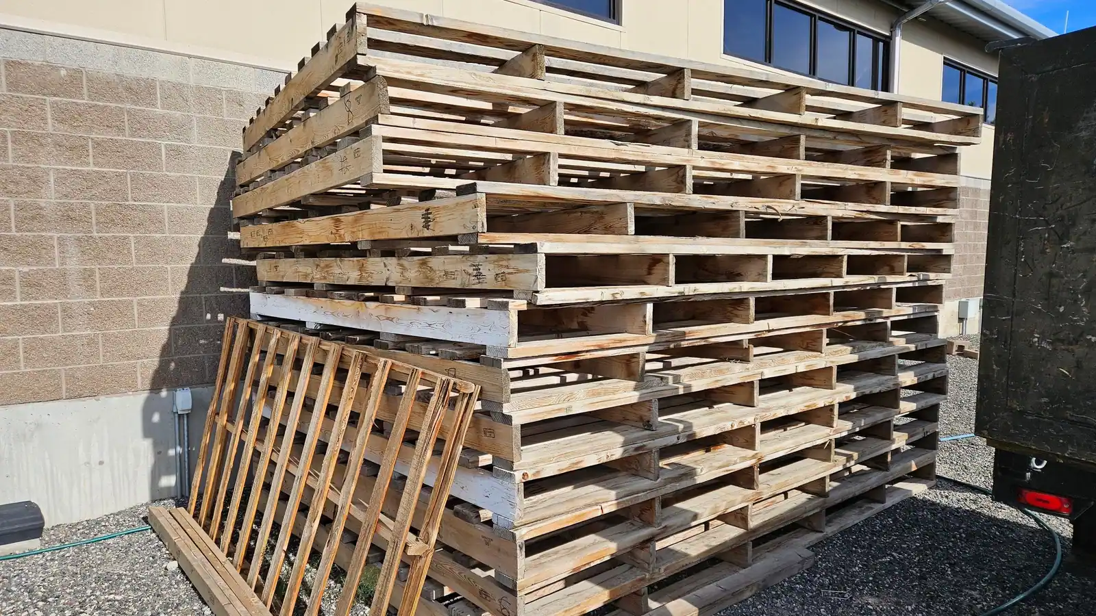 A tall stack of old wood pallets behind a business