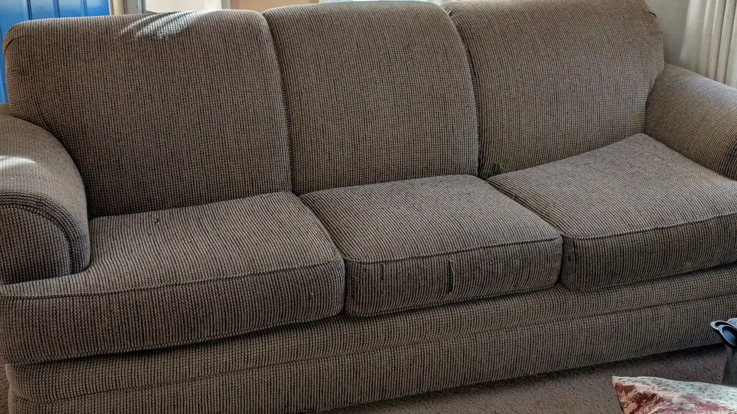 A brown three-seat sofa in a living room, ready to go