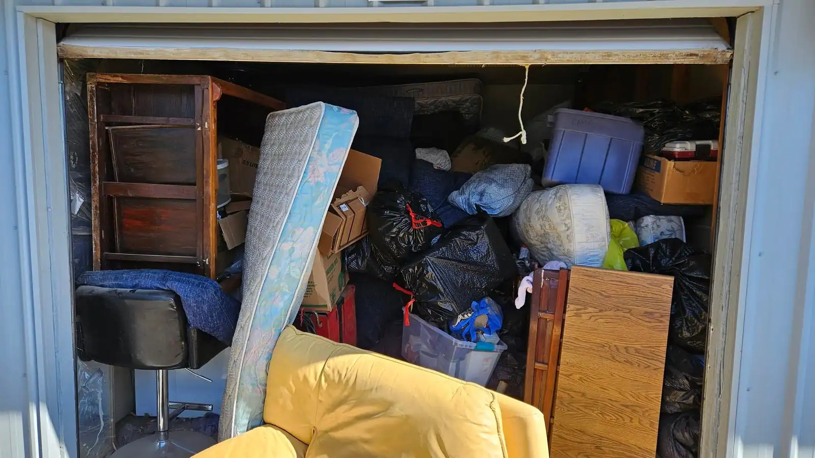 A storage unit packed to the door with furniture and bags