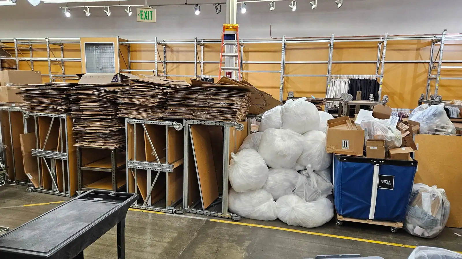 A store backroom with stacks of flattened cardboard, bagged packing and fixtures