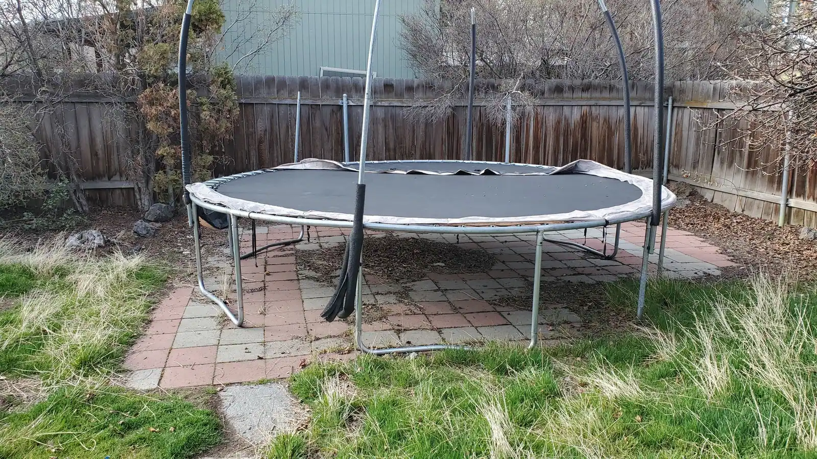 An old round trampoline with a safety net frame in a backyard