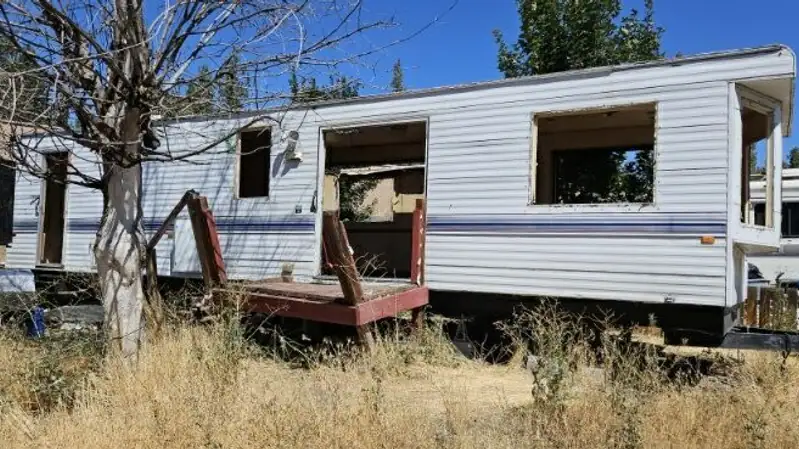 An old travel trailer with its windows out, waiting to be torn down