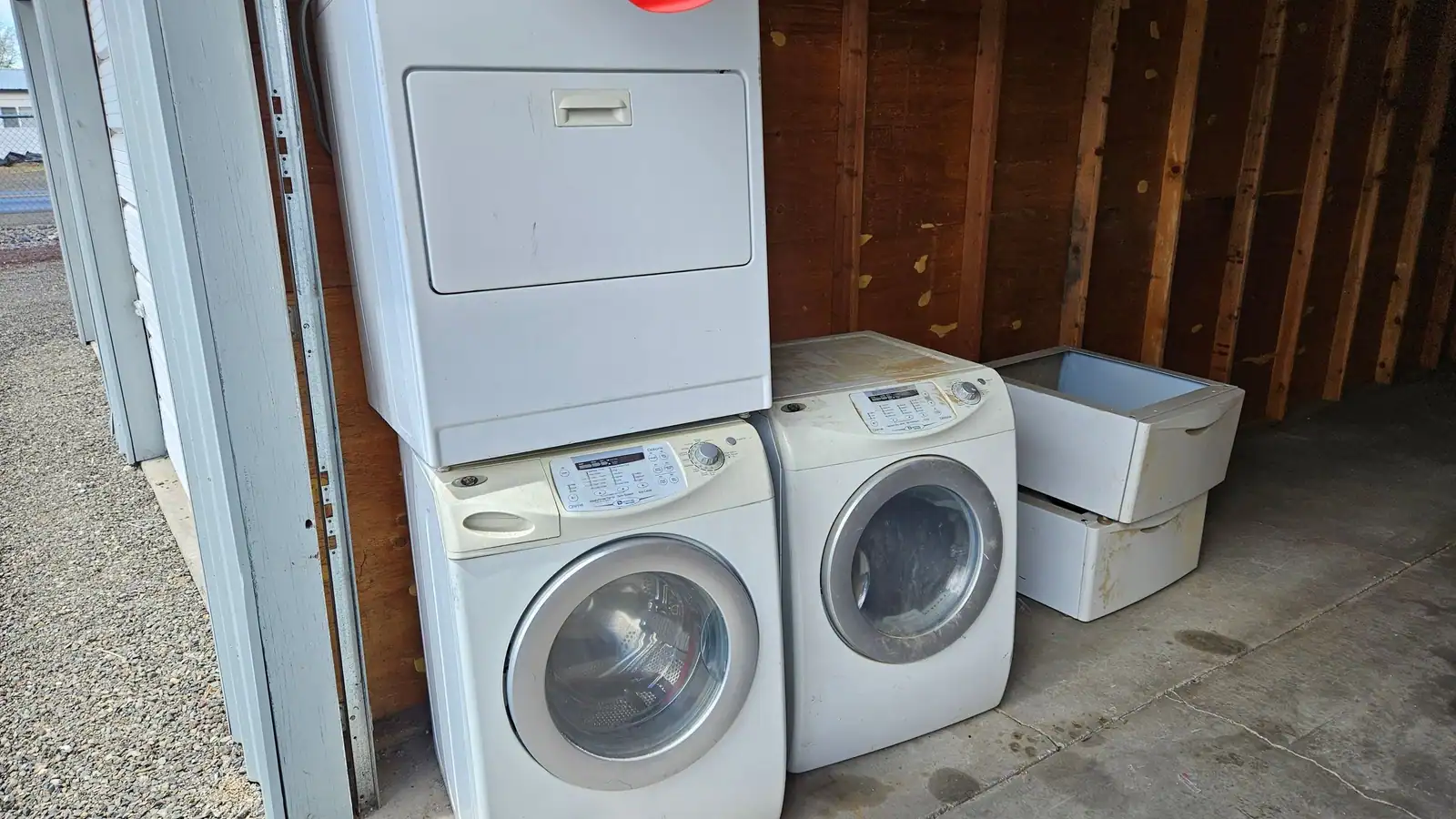 A washer, a dryer and a second washer lined up in a carport